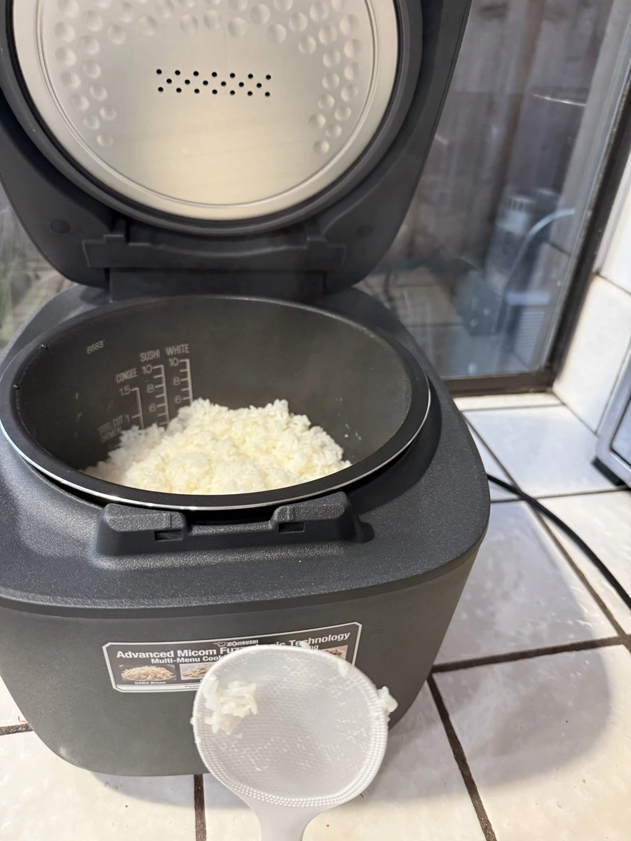 Close-up of a matte-black nonstick inner pot with crisp white water measurement lines and rinsed white rice
